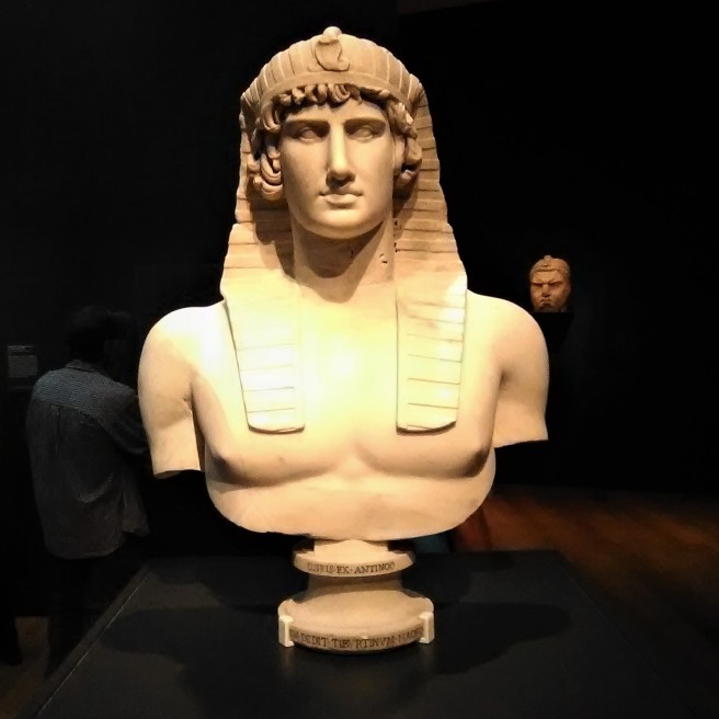 Bust of Antinous. Roman, 131-138 CE; found in Hadrian's Villa, Tivoli, Italy. Antinous, the young companion of the emperor Hadrian (ruled 117-138 CE), drowned in the Nile in 130 CE and was posthumously honored with a cult that was celebrated throughout the Roman Empire. Hadrian's Villa at Tivoli displayed numerous portraits of Antinous in the guise of a pharaoh or the underworld god Osiris, wearing a traditional nemes headdress with a uraeus (royal cobra).